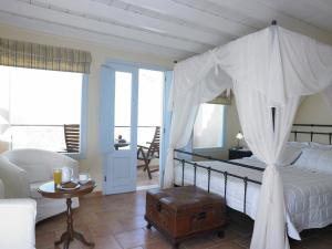 a bedroom with a canopy bed and a living room at Suites of the Gods Cave Spa Hotel in Megalokhori