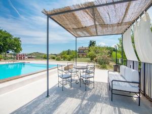 un patio avec une table et des chaises à côté d'une piscine dans l'établissement Belvilla by OYO Giglio, à Ascoli Piceno