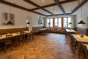 un restaurante con mesas y sillas de madera y ventanas en Schattenhofer Braugasthof en Beilngries