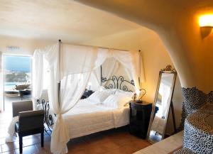 a bedroom with a canopy bed and a mirror at Suites of the Gods Cave Spa Hotel in Megalokhori