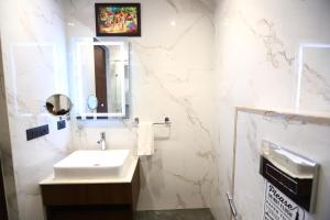La salle de bains blanche est pourvue d'un lavabo et d'un miroir. dans l'établissement Hotel Sanca International Patel Nagar Delhi - Couple Friendly Local IDs Accepted, à New Delhi
