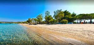 una playa de arena con árboles y agua en Mario's Luxury Maisonette en Neos Marmaras