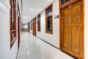 um corredor com uma porta de madeira e um piso de azulejo em OYO 90891 Parang Kusumo Residence em Krembangan