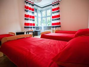 a room with two beds with red sheets and a window at Hostel 4you in Bielsko-Biala