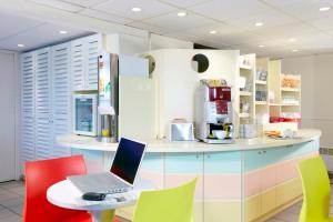 a kitchen with a laptop on a table with chairs at Premiere Classe Dunkerque Est Armbouts Cappel in Armbouts-Cappel