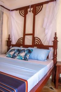 ein Bett mit einem Holzrahmen und blauen Kissen in der Unterkunft Amarrosi Buffalo-One Bedroom apartment, Mtwapa in Mtwapa