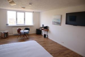 um quarto com uma cama, uma mesa e uma televisão em Bed & Coffee Maricoweg em Den Burg