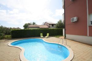a swimming pool in a yard next to a building at Apartment Percic with Shared Pool in Vabriga