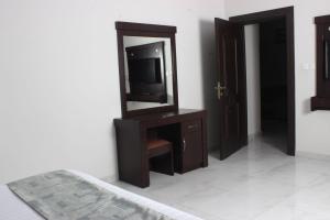 1 dormitorio con TV y tocador con espejo en Rayat Alshalal Hotel 2, en Hafr Al Batin
