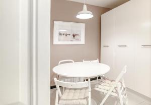 een witte eetkamer met een witte tafel en stoelen bij Piso catalogado en el centro de Gijon in Gijón