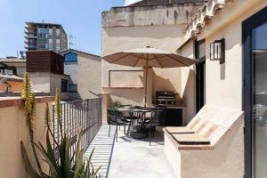 un patio con sombrilla, mesa y sillas en Velo Vern 3 Luxury penthouse w views of city wall en Girona