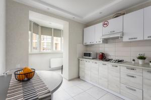 una cocina con armarios blancos y una mesa. en 0131 Apartment near Zhulyany airport New complex, en Kiev