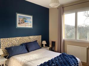a bedroom with a bed with a blue wall at Au bras d'argent Léa et Vincent in Auros
