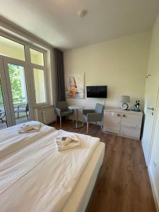 a bedroom with a bed and a table and a tv at Strandresidenz Villa Verdi in Kühlungsborn