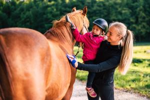 a woman and a child standing next to a brown horse at EkoTurizem Hudičevec in Postojna