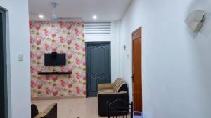 a living room with a couch and a tv on a wall at Bamba Flat in Colombo