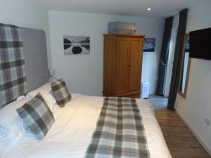 a bedroom with a bed with plaid pillows on it at Dreamwood Cottage, Loch Lomond, Luxury Apartment. in Glasgow