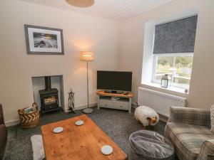 een woonkamer met een bank, een tv en een tafel bij Tyn Lon in Pwllheli