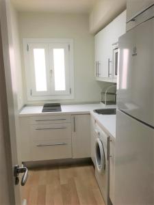 a white kitchen with a sink and a refrigerator at Apartamento Plaza de Los Naranjos Marbella in Marbella