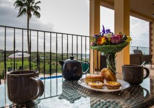 Algarve Luxury Home With Private Heated Pool II في سيلفيس: طاولة مع صحن من المعجنات و إناء من الزهور