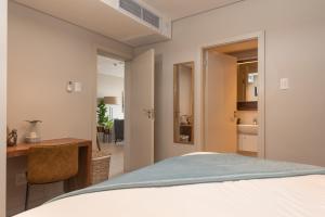 1 dormitorio con cama, escritorio y baño en Zimbali Suites 411, en Ballito