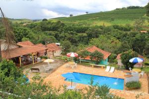 a house with a swimming pool with umbrellas at Pousada Cachoeirinha in Baependi