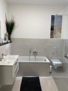 a bathroom with a tub and a sink and a toilet at Schwartz GmbH in Greiz