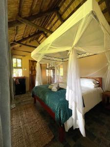 1 dormitorio con 1 cama con dosel en Maramba River Lodge, en Livingstone