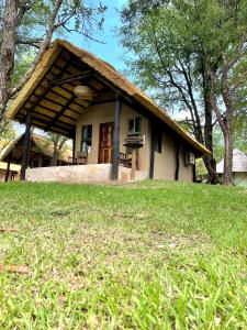 a house with a thatched roof on top of a field at Maramba River Lodge in Livingstone