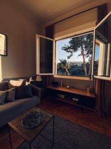 a living room with a couch and a large window at Live Life Acropolis in Athens