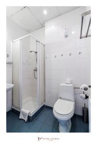 a white bathroom with a toilet and a shower at Hotel Colibra in Warsaw