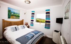 Un dormitorio con una cama con almohadas a rayas y una ventana en The Old Dairy, Land's End, Sennen, en Sennen