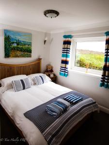 a bedroom with a bed with pillows and a window at The Old Dairy, Land's End, Sennen in Sennen