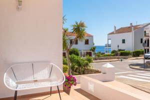 a white chair on a balcony with a view of a street at Apartamentos Annabel's I in Cala Galdana
