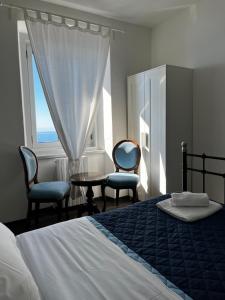 a bedroom with a bed and two chairs and a window at Villa Tergeste in Trieste