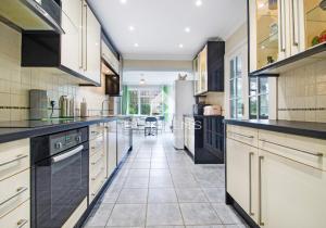 a large kitchen with white cabinets and black counter tops at The Avenues, Frinton on Sea in Frinton-on-Sea
