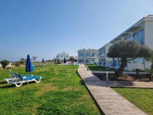 a lawn with chairs and an umbrella and a building at Ocean Suites Luxury Apartments in Protaras