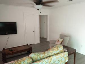 a living room with a couch and a flat screen tv at Welcome to Pineapple House! in Pensacola