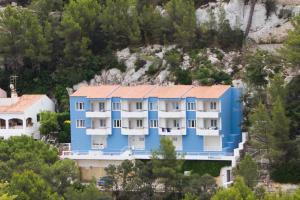 un edificio azul y blanco en una montaña en Cala Galdana Apartamentos El Rio 1 habitación, en Cala Galdana