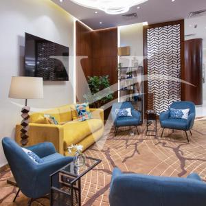 Viola Hotel Apartments في الشارقة: غرفة معيشة مع أريكة صفراء وكراسي زرقاء