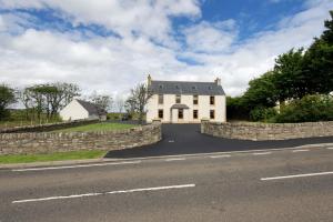 a large white house with a stone wall next to a road at Albion House- Highlands in Lybster