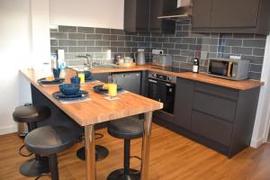 a kitchen with a wooden island with bar stools at Wisteria 2 bed House - STAYSEEKERS in Salisbury