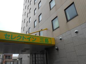 a building with a yellow sign in front of it at Select Inn Mishima in Mishima