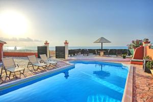 a pool with chairs and the ocean in the background at Beach Villa Athanasia - villa with private pool on the beach by PosarelliVillas in Acharavi