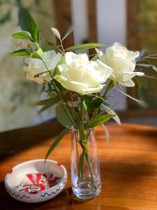 un vase avec des roses blanches à côté d'un bol dans l'établissement Hotel Casa Romaneasca, à Otopeni