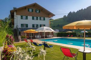 a pool with chairs and umbrellas next to a building at Garni Hotel Melissa in Castelrotto