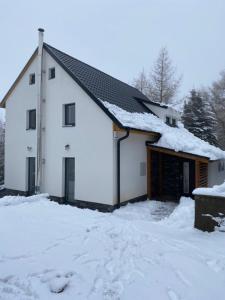 Biały dom z śniegiem na dachu w obiekcie Chalupa Haj 109 w mieście Loučná pod Klínovcem