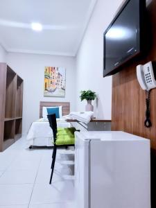 a room with a bed and a desk with a television at Hotel Cantinho Verde in Teixeira de Freitas
