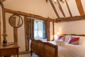 a bedroom with a bed and a mirror and a window at Water Cottage, a perfect ancient House in Suffolks prettiest tiny village in Kersey