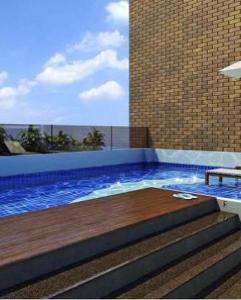 uma piscina com um deque de madeira e escadas em Flat Essenciale Style1602 em Goiânia